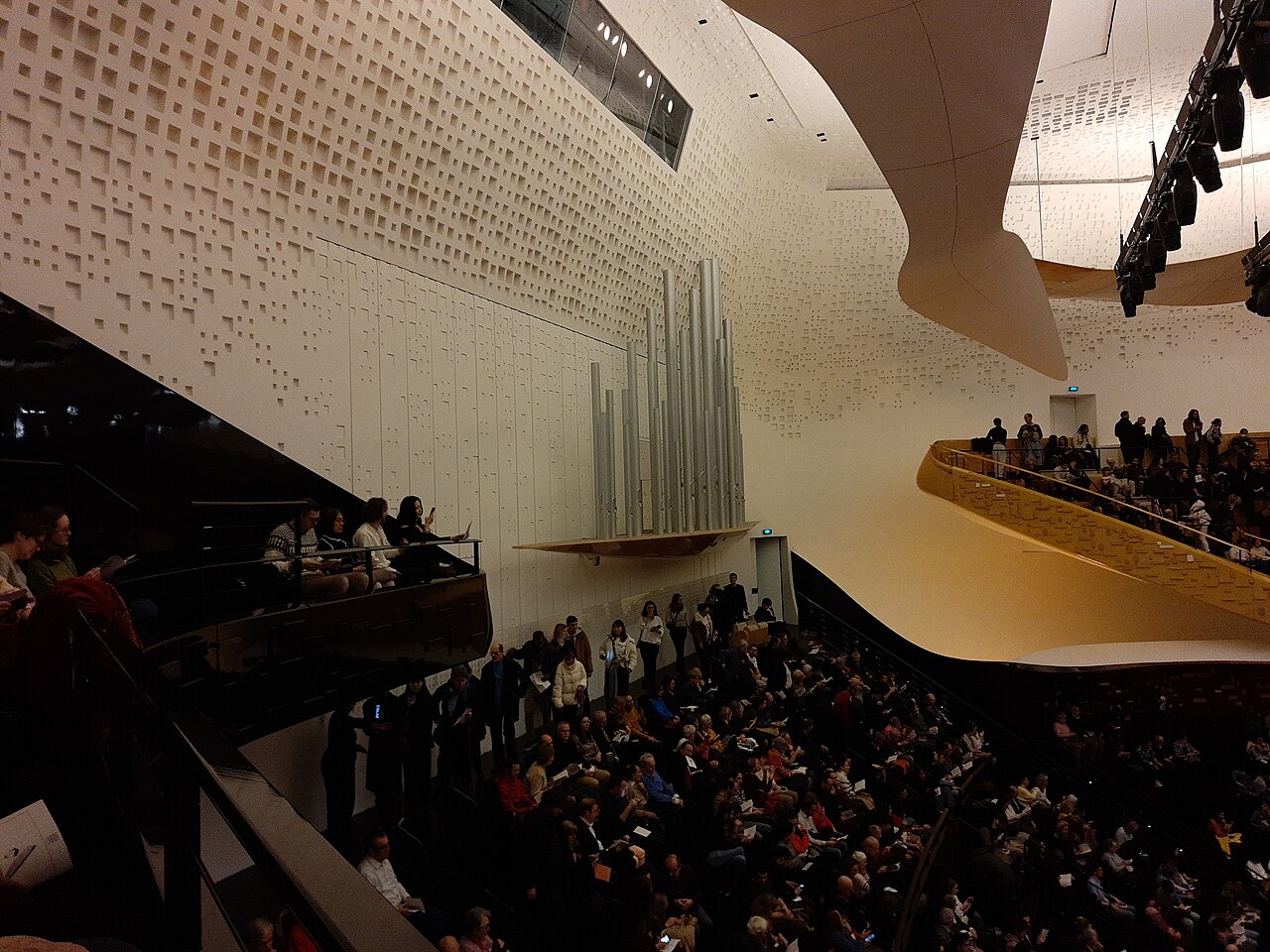 Salle de concert contemporaine, gradins de bois et volumes enveloppants